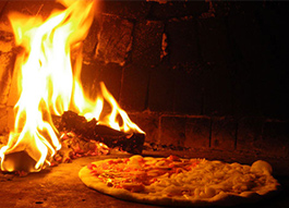 石窯の中で美味しく焼かれているピザの画像